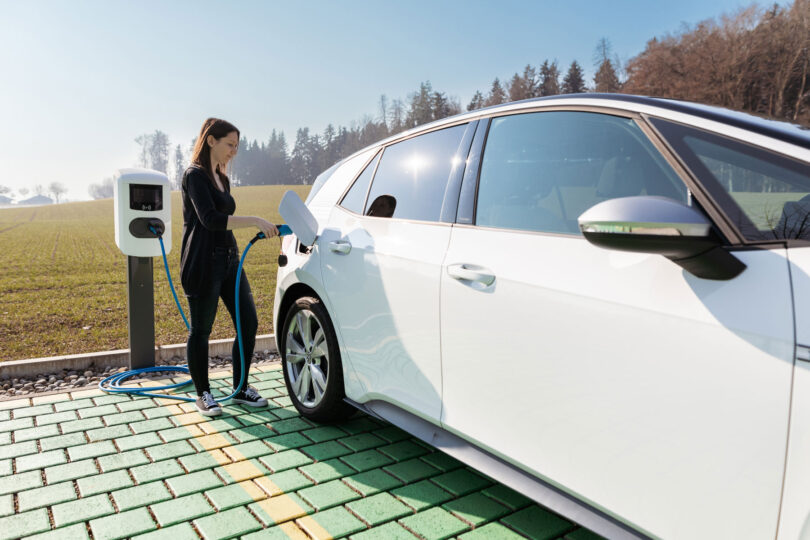 Frau lädt ihr Elektro-Auto an einer Ladestation